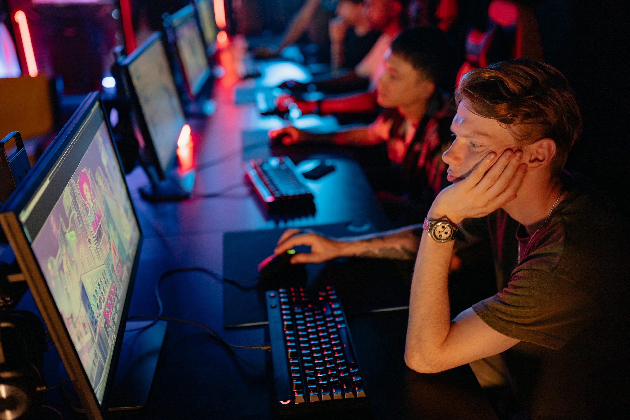 Gamers intensely focused on a computer game during an online esport competition in a dimly lit arena.